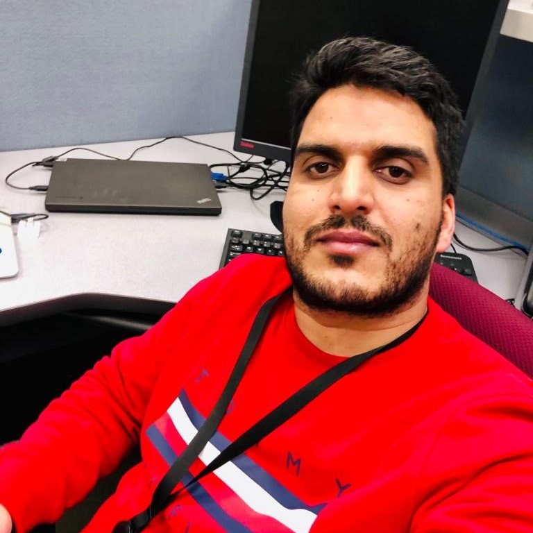 Dr. Basit Yousuf sitting in front of a computer wearing a red shirt