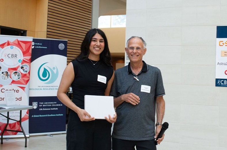 Dr. Ed Conway holding an award to Simrat Binning