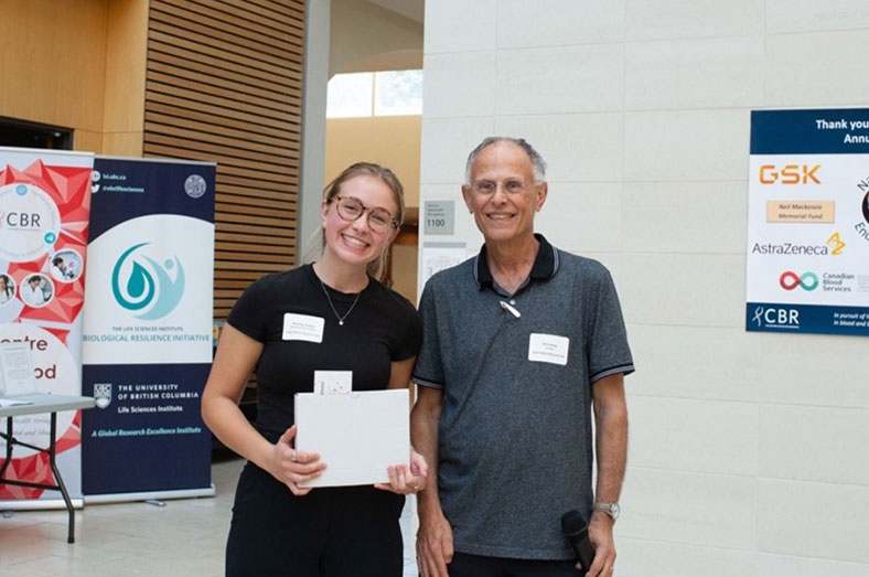 Madelyn Tisdale holding an award with Dr. Ed Conway