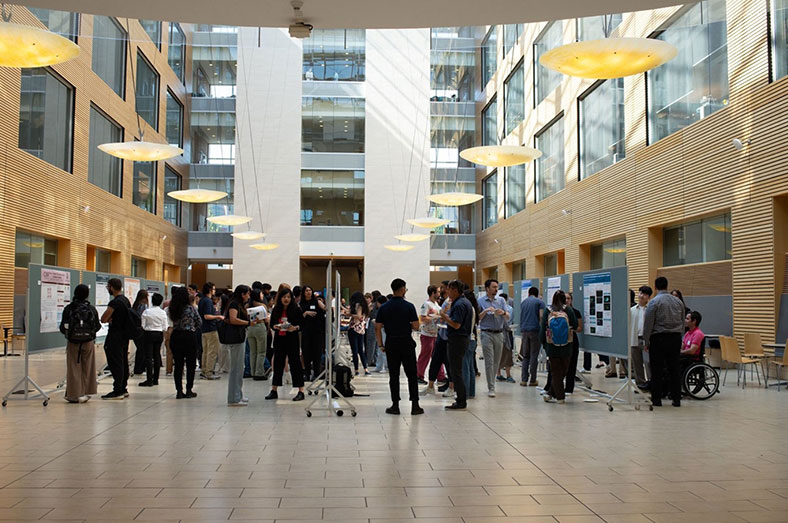 Attendees in a hall with posters during Research Day