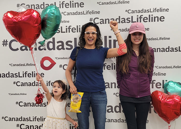 Three people in front of a CanadasLifeline wall with balloons.
