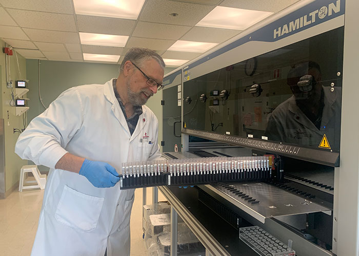 Douglas Ems handling some test tube trays into the machine