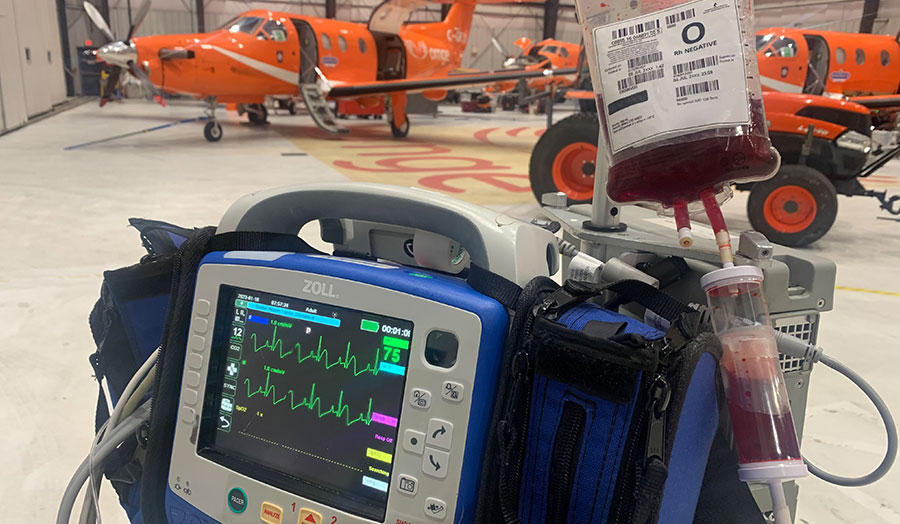 Machine for air ambulances with a red blood bag with orange airplanes in the back