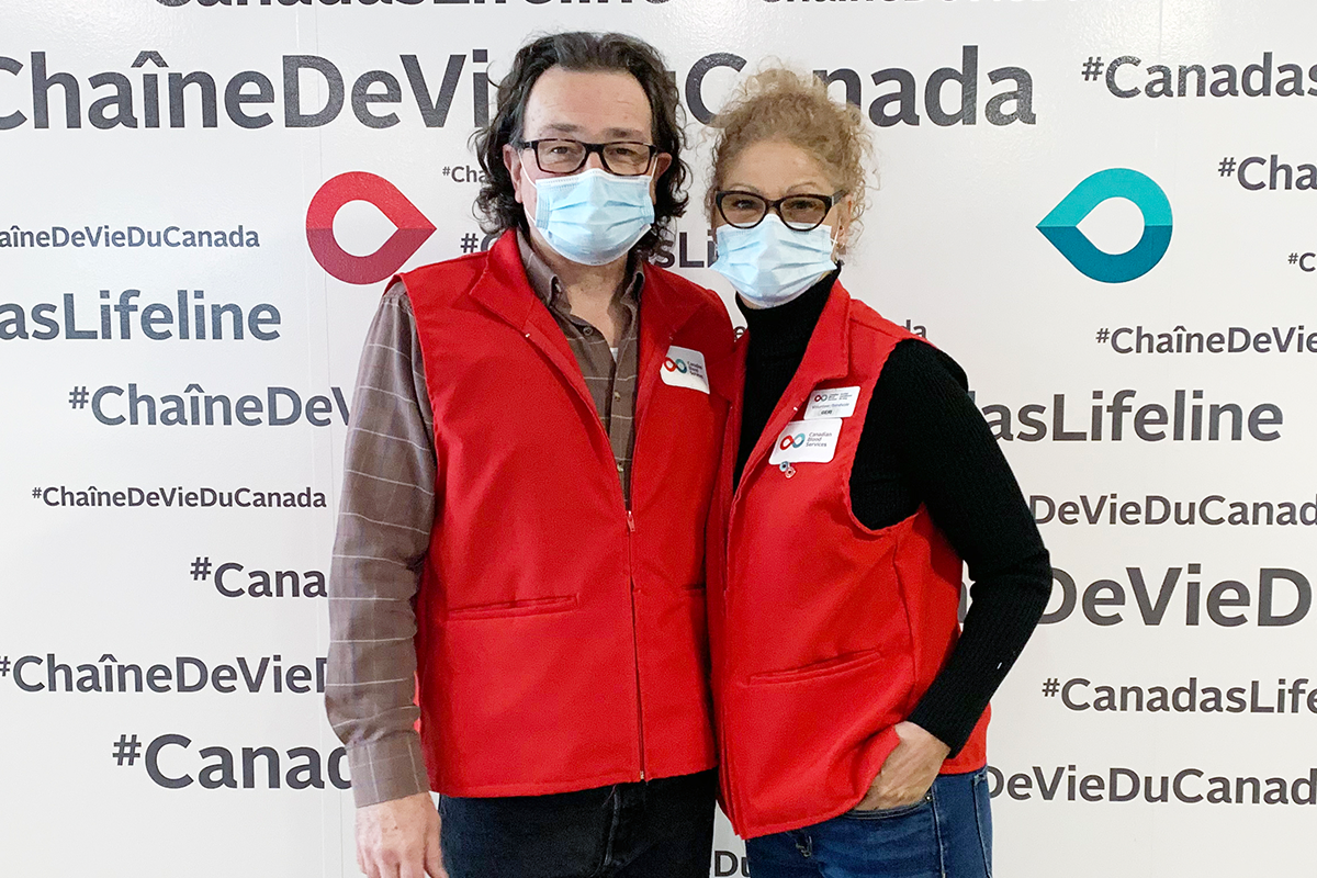 Plasma donor centre volunteer couple in front of Canada’s Lifeline sign