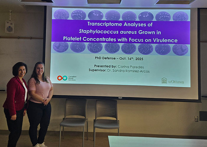 Carina Paredes and Dr. Sandra Ramirez-Acros in front of a projector screen presentation