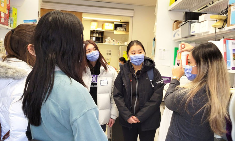 Students wearing masks taking a tour of a research lab