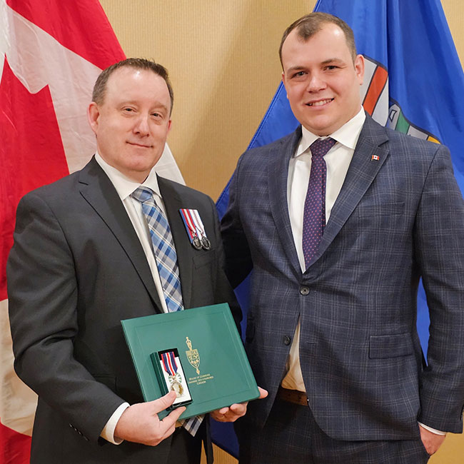 Person holding an award beside someone else