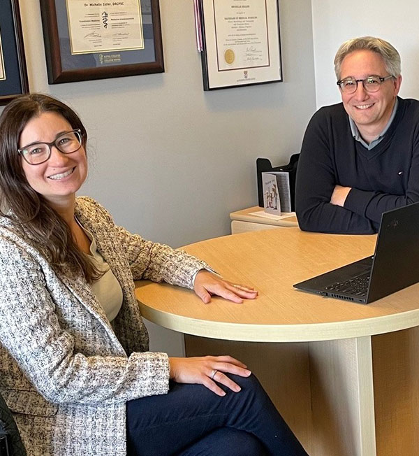 Two people sitting at a desk with a laptop