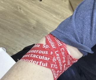 Blood donor's arm with red pressure bandage covered in words
