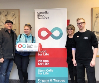 Husband and wife with adult children at blood donor centre