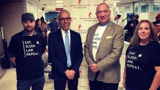 Ontario Paralegal Association and Dr Graham Sher posing together in front of a banner stand in a donor centre.