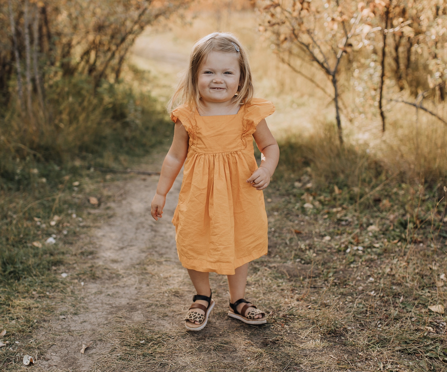 Young girl in orange summer dress and sandals outdoors