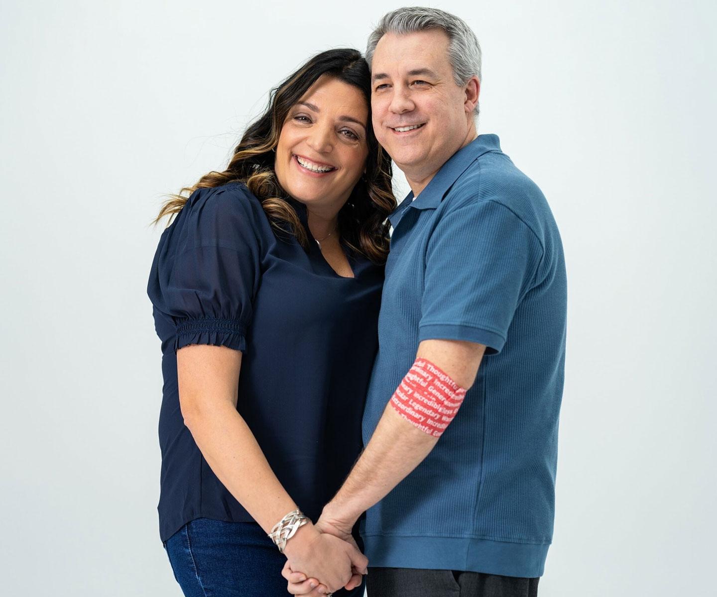 Blood recipient holding hands with blood donor husband wearing an arm wrap