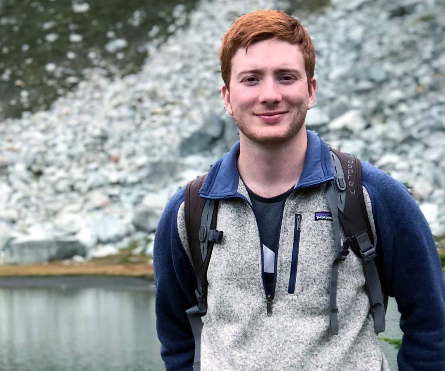 Young man in rocky, hilly area next to a lake