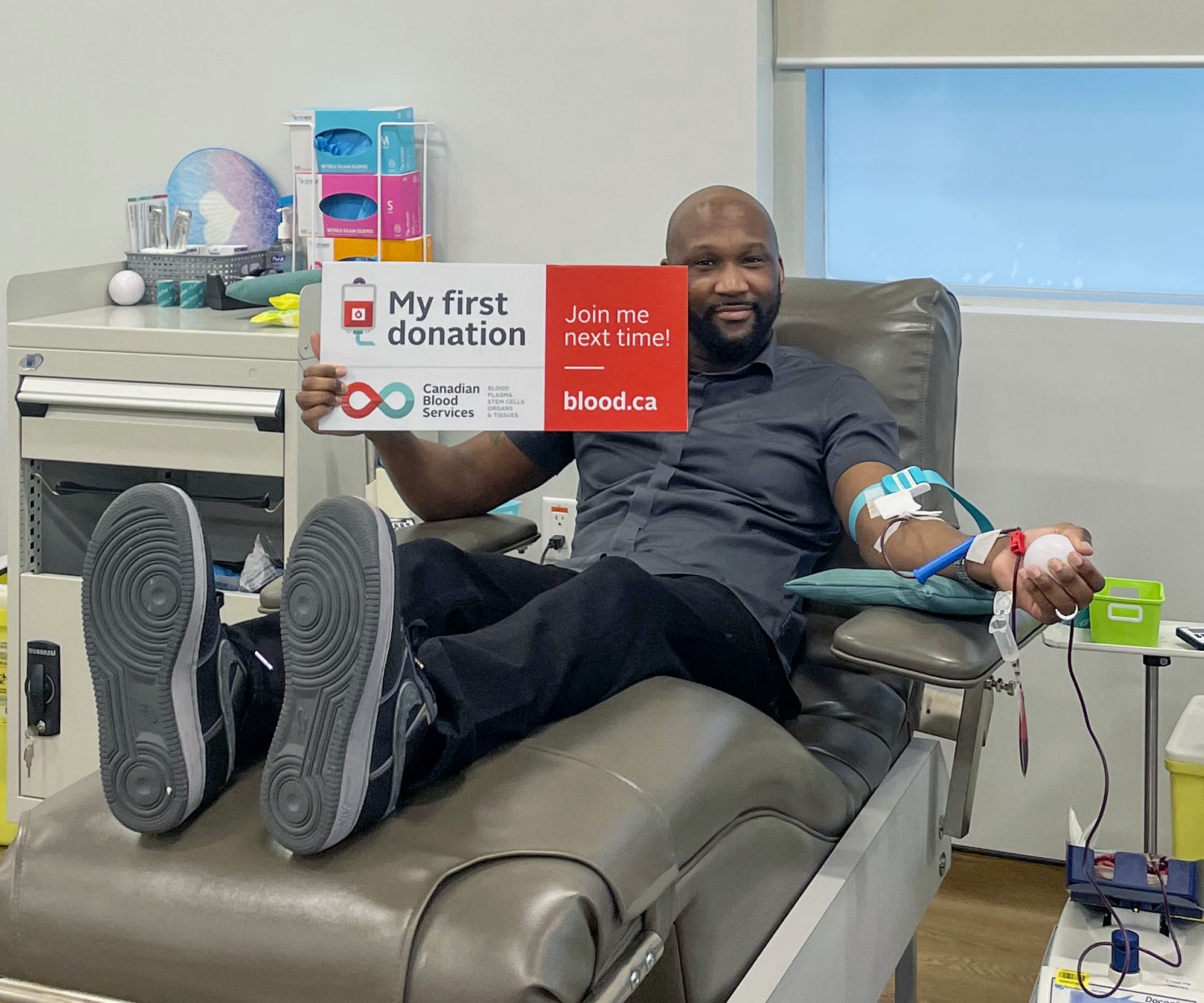 Blood donor in donation chair with sign that says My first donation