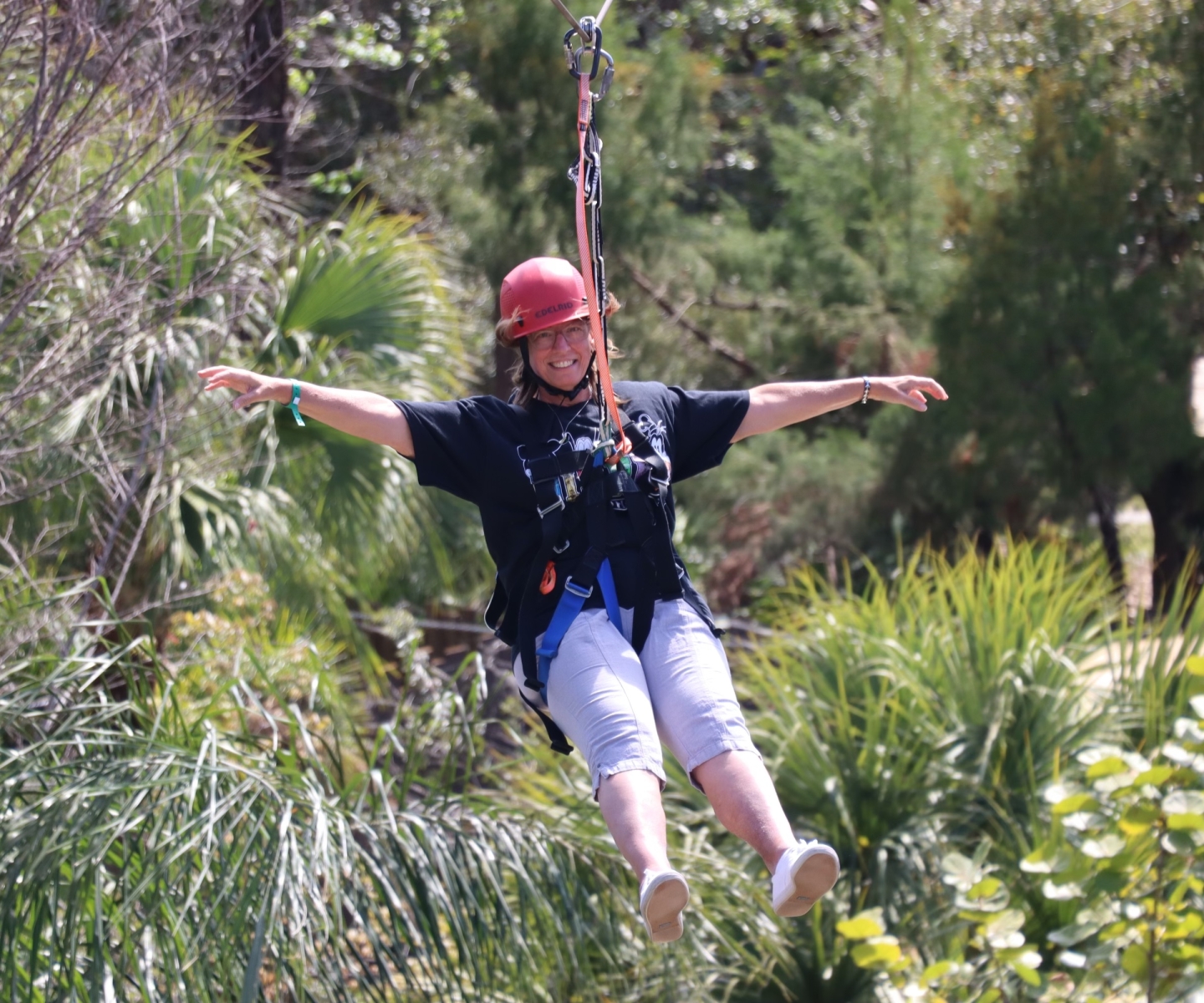 Woman rides a zip line through a forest