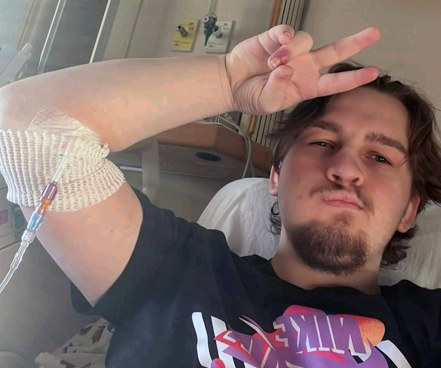 Blood recipient giving peace sign in hospital bed