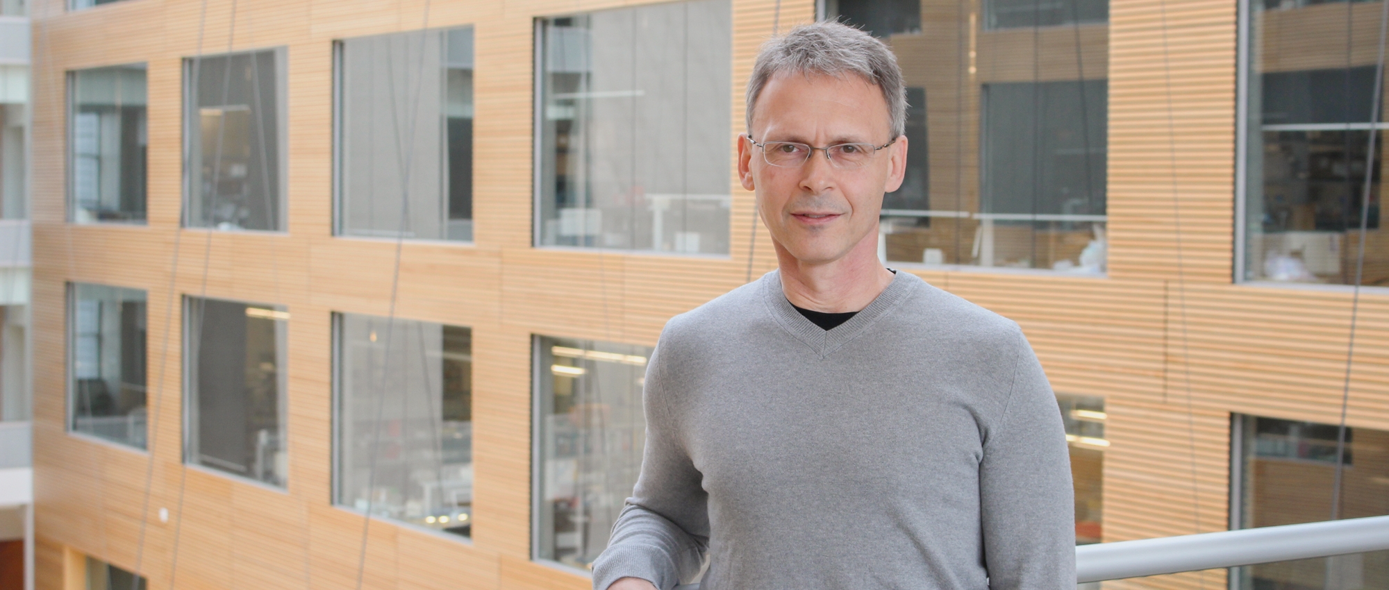 Image of Dr. Ed Pryzdial wearing a grey shirt and glasses with grey hair standing at the Canadian Blood Services Head office