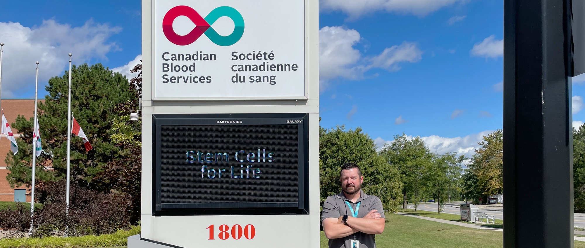 Stem cell donor stands in front of Canadian Blood Services’ signboard in Ottawa.