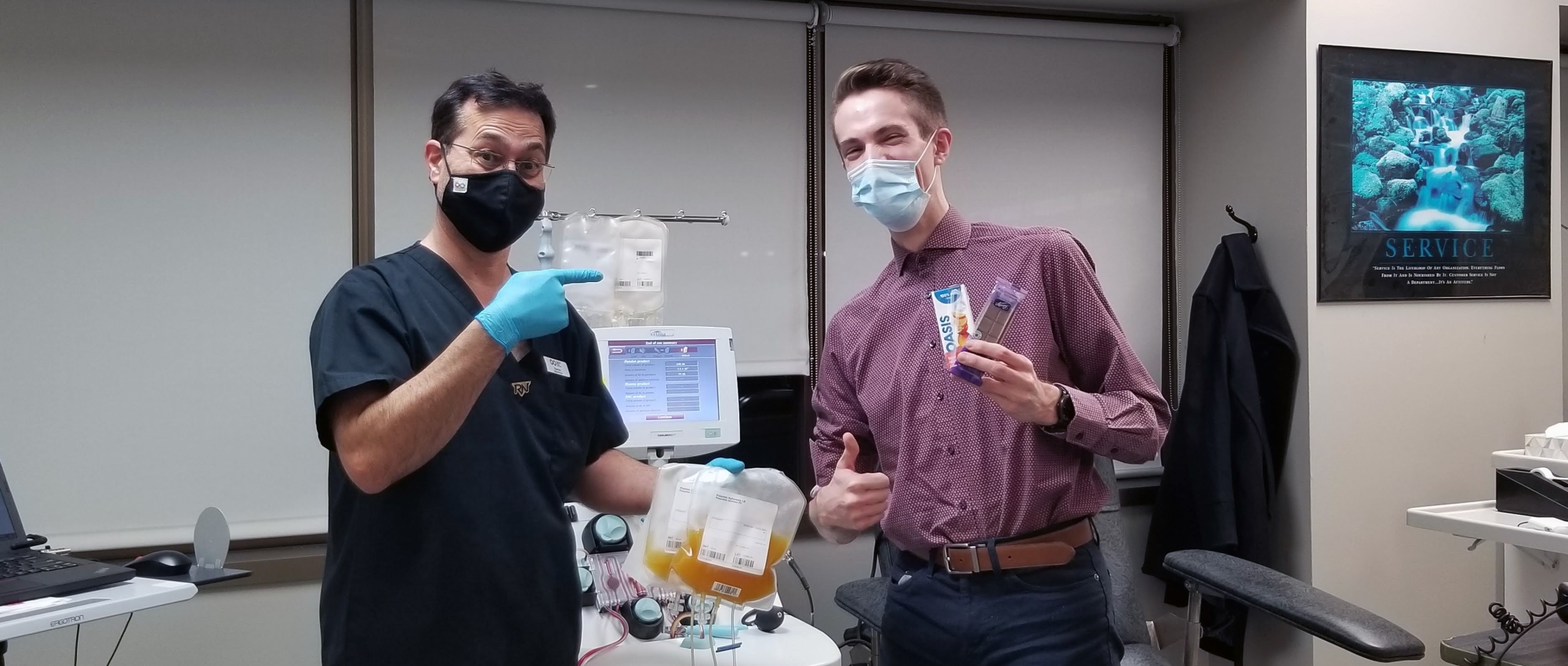 Nurse holds platelet donation while smiling and pointing at platelet donor holding post-donation snacks