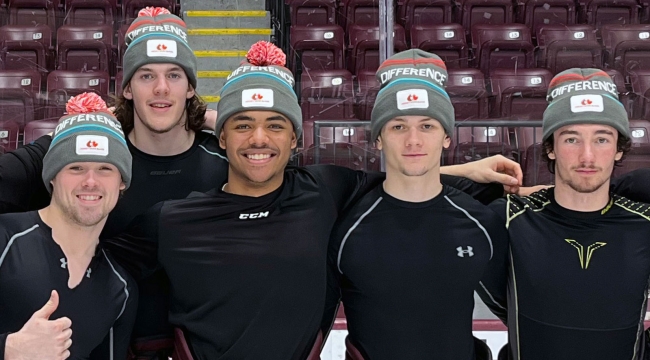 Hockey players on ice with Hockey Gives Blood tuques