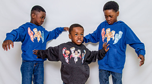 Hezekiah, Joiakim and Micah Felix pose in shirts that display the superhero characters in the book The Battle of Ottogatz. 