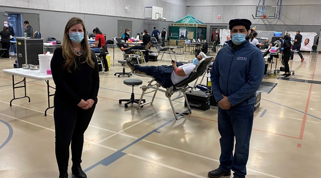 Staff in a gym converted to a blood collection centre with donors in the background