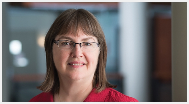 Image of Dr. Dana Devine wearing glasses and with a red shirt.