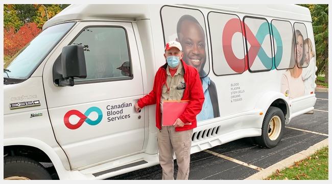 Image of Volunteer Life Bus driver David Neu standing outside of a Canadian Blood Services branded bus