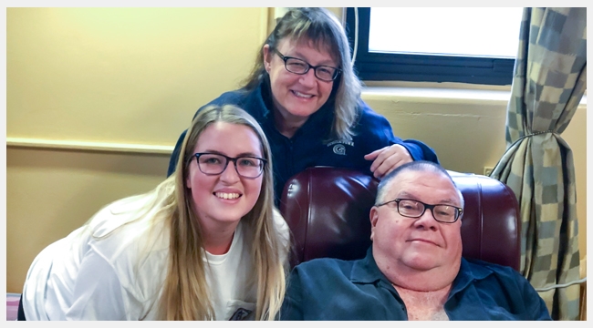 Image of Bruce Phinney with wife and daughter sitting in a recliner