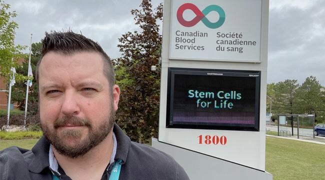 Stem cell donor stands in front of Canadian Blood Services’ signboard in Ottawa.