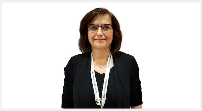 A woman with short brown hair and glasses wearing a Canadian Blood Services Brand Ambassador lanyard around her neck.