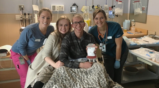 Mike Wark, who had a stem cell transplant, holds a bag of donated stem cells while surrounded by his wife and hospital staff.