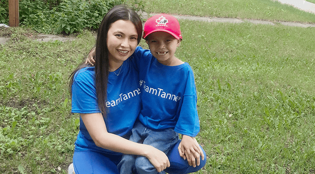 Miranda McLeod and her son Tanner pose together on their lawn. Miranda carries Tanner on her lap, weeks after his stem cell transplant.