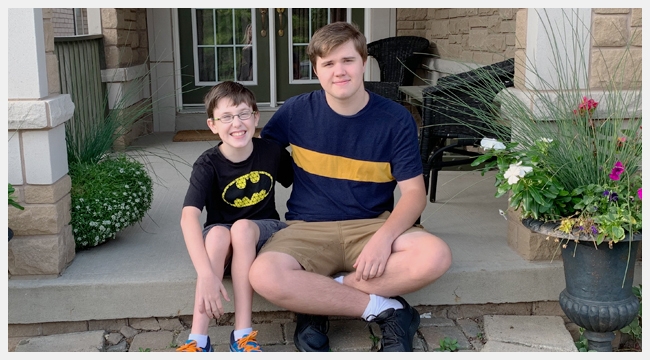 Nolan Clark, a teen who donated blood for the first time, sits on a porch with his younger brother Nicholas who had blood transfusions as an infant.