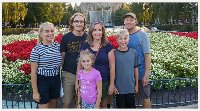 Thumbnail Image of Scott Norton and Nadine Norton with their children and Elsa Norton standing in front of garden of flowers at the amusement park
