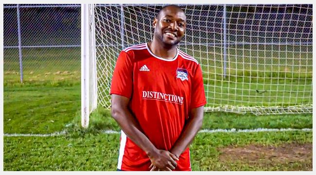 Image of Dujon Donaldson wearing a red soccer uniform in front of a soccer goal post