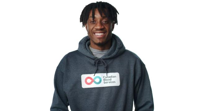 Hockey Gives Blood Player Ambassador Zack Stringer smiles in a Canadian Blood Services pullover hoodie